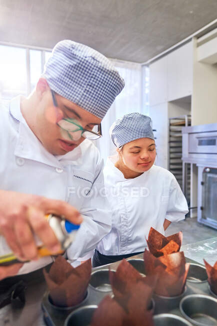 Estudantes com Síndrome de Down assar muffins na cozinha — Fotografia de Stock