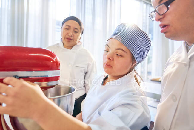 Étudiants atteints de trisomie 21 utilisant un mélangeur de stand en classe de cuisson — Photo de stock