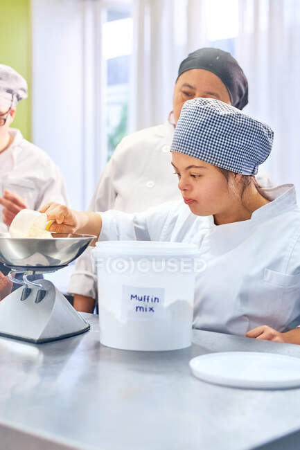 Young woman with Down Syndrome measuring muffin mix — Stock Photo