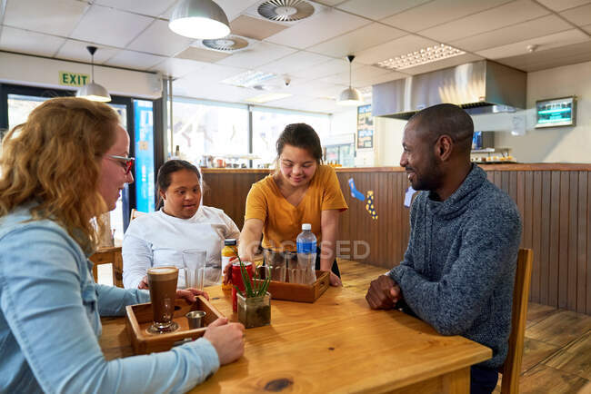 Junge Serviererin mit Down-Syndrom serviert Getränke im Café — Stockfoto