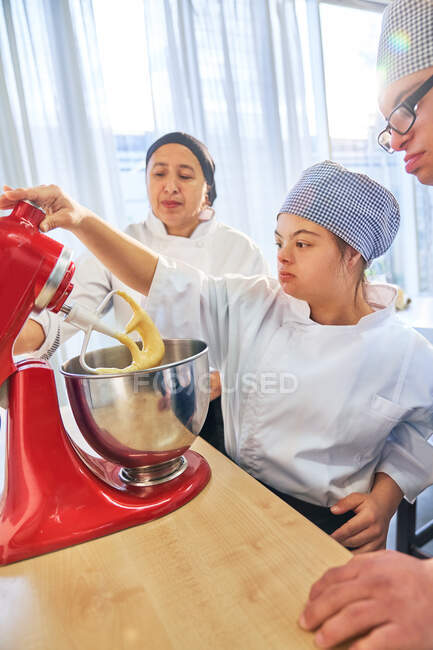 Студенти з синдромом Дауна, послуговуючись змішувальником для випічки, — стокове фото