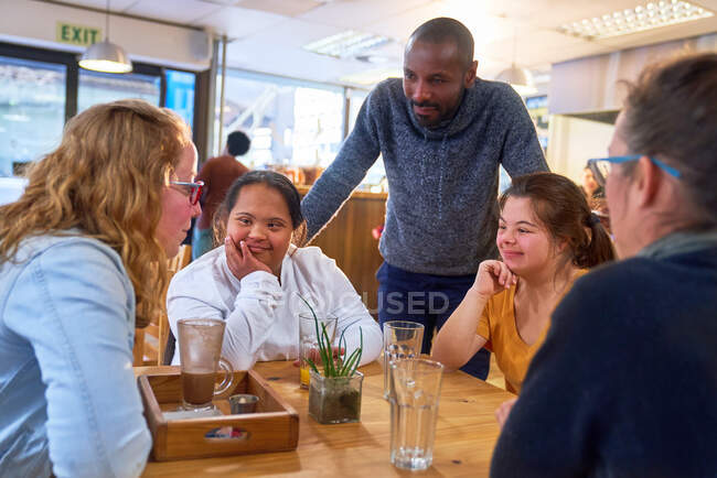 Junge Frauen mit Down-Syndrom im Gespräch mit Freunden im Café — Stockfoto