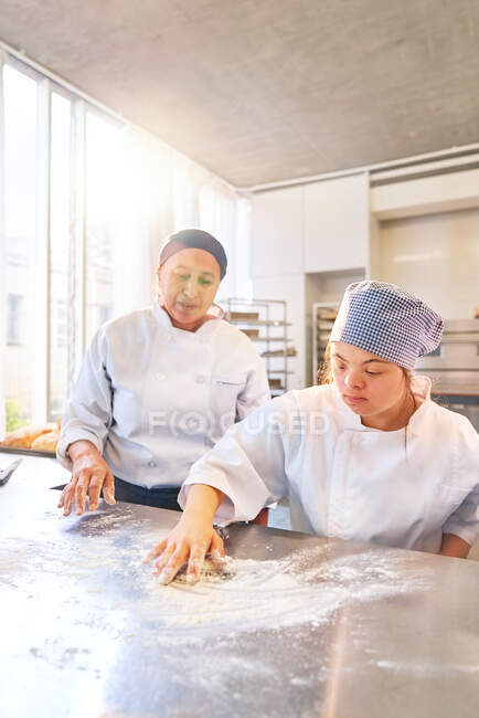 Instructeur de cuisson et jeune étudiant avec surface de farine de trisomie 21 — Photo de stock