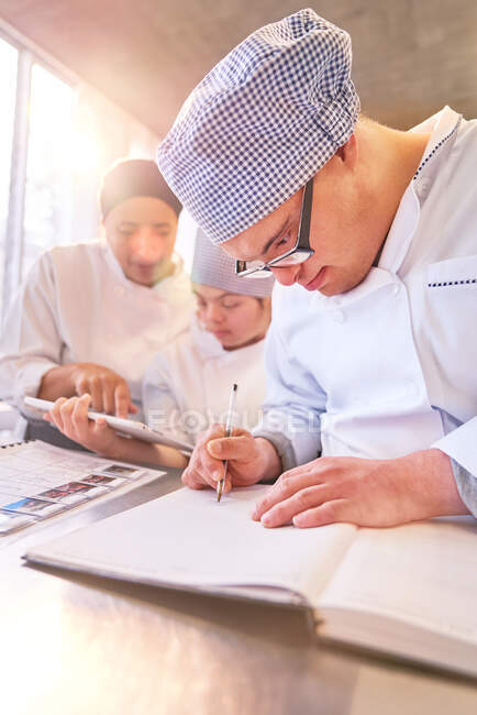 Students with Down Syndrome looking at recipes in kitchen — Stock Photo