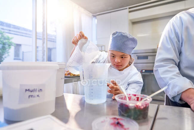 Сфокусована молода студентка з синдромом Дауна випічкою на кухні — стокове фото