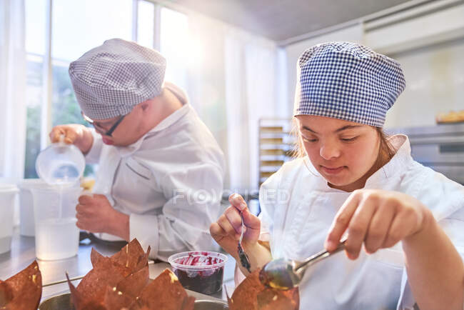 Young woman with Down Syndrome baking muffins in kitchen — Stock Photo
