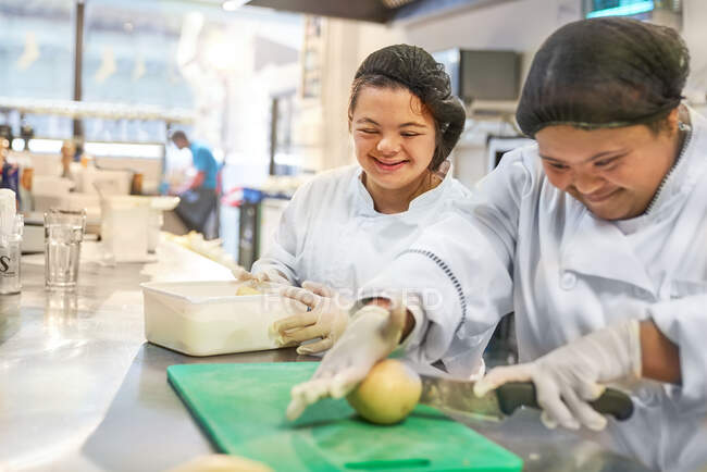 Mujeres jóvenes felices con Síndrome de Down cocinando en el restaurante - foto de stock