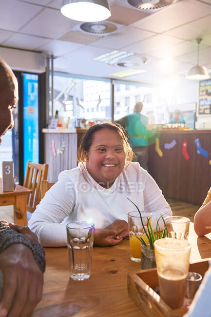 Портрет счастливой молодой женщины с синдромом Дауна в кафе с друзьями — стоковое фото