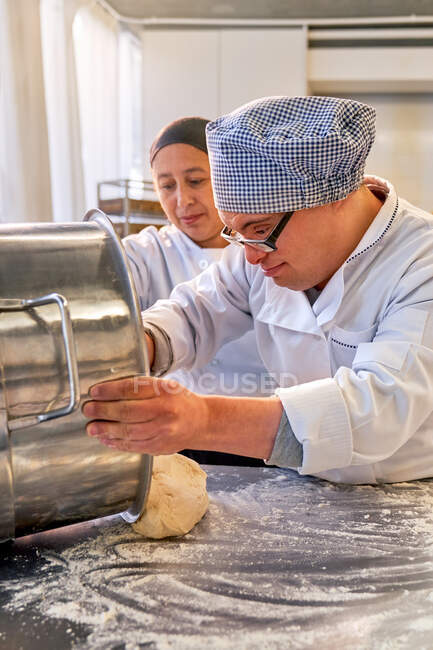 Ученик с синдромом Дауна учится печь на кухне — стоковое фото