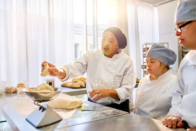 Шеф-повар учит студентов с синдромом Дауна печь — стоковое фото