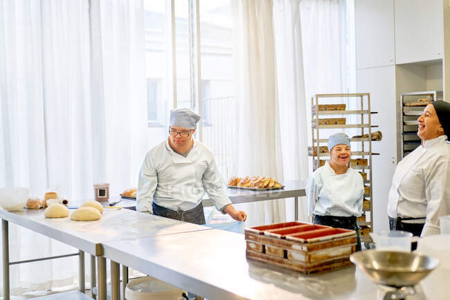 Chef feliz e alunos com Síndrome de Down assar na cozinha — Fotografia de Stock