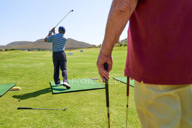 Golfista masculino praticando no campo de golfe ensolarado driving range — Fotografia de Stock