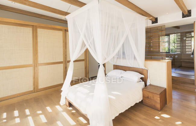 Белые марлевые шторы на кровати с балдахином в современной, роскошной витрине интерьера спальни — стоковое фото