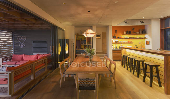 Illuminated modern, luxury home showcase interior dining room open to patio — Stock Photo