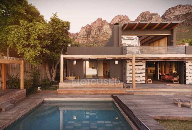 Montañas detrás de la casa moderna y lujosa casa de escaparate exterior con piscina. - foto de stock
