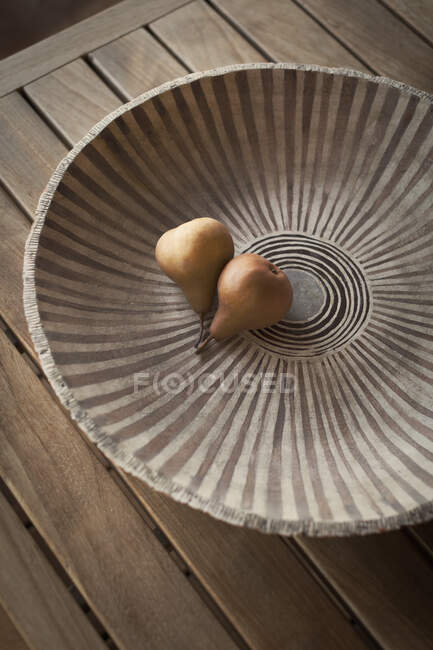 Живі груші в керамічній посудині з візерунком на дерев 