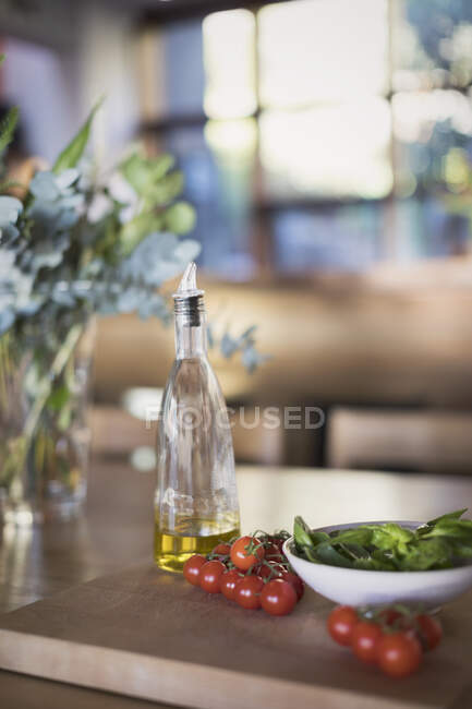 Stilleben frische, reife Kirschtomaten, Basilikum und Olivenöl auf Schneidebrett — Stockfoto