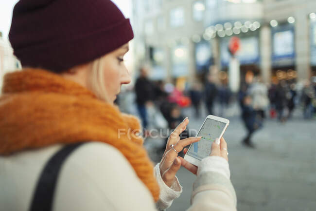Jeune femme utilisant le GPS sur un téléphone intelligent dans une rue urbaine — Photo de stock