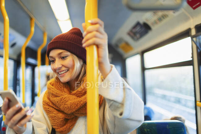 Молода жінка смс зі смартфоном в автобусі — стокове фото