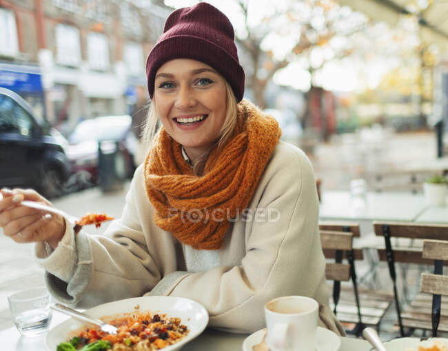 Portrait smiling woman eating lunch at autumn sidewalk cafe — Stock Photo