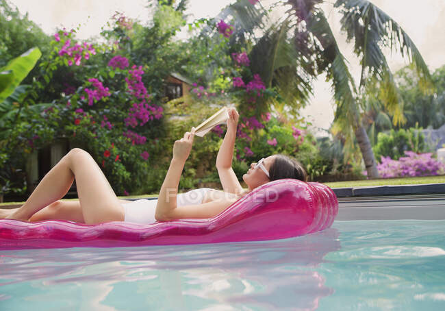 Gelassene Frau entspannt sich, liest Buch auf Floß im Schwimmbad — Stockfoto