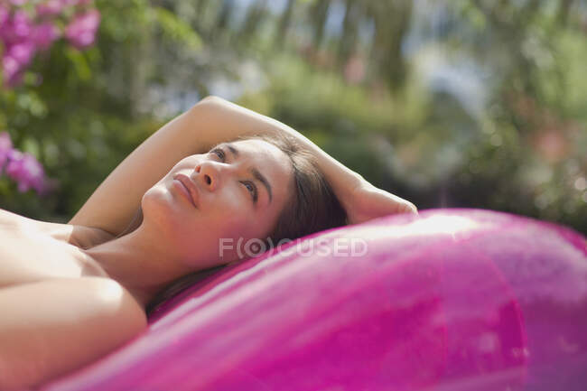 Спокойная женщина отдыхает на розовом надувном плоту — стоковое фото