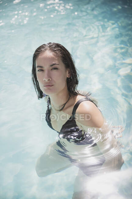 Retrato mulher confiante nadando na piscina ensolarada de verão — Fotografia de Stock