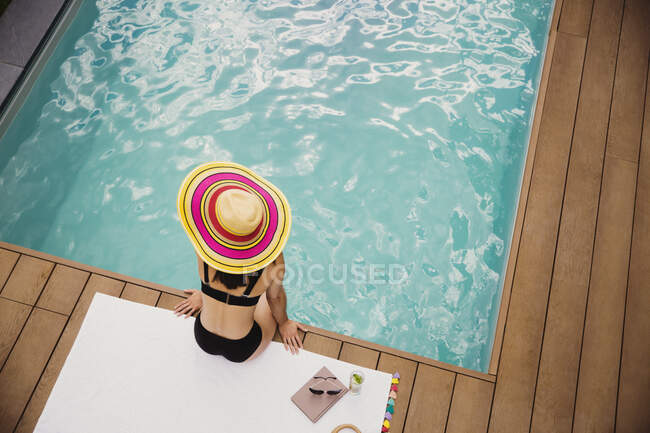 Frau mit Sonnenhut und Bikini entspannt am Pool — Stockfoto