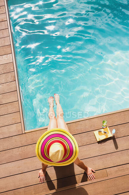Woman in sun hat relaxing at sunny summer poolside — Stock Photo