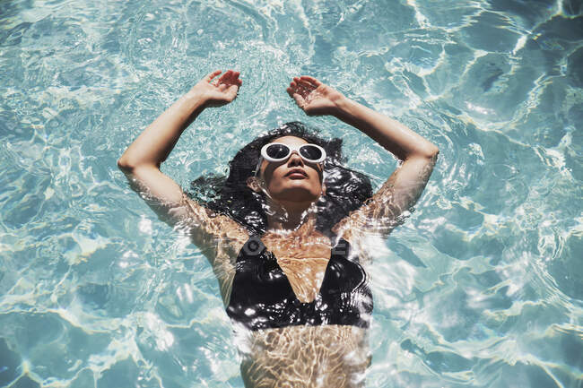 Donna serena galleggiante nella soleggiata piscina estiva — Foto stock