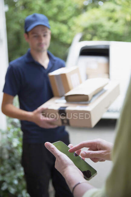 Woman signing smart phone for deliveryman at front door — Stock Photo