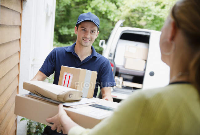 Deliveryman delivering packages to woman at front door — Stock Photo