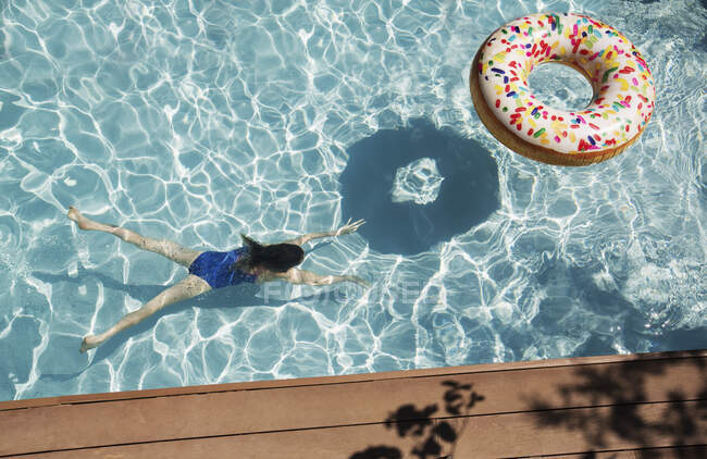 Chica nadando bajo el agua en la piscina soleada - foto de stock