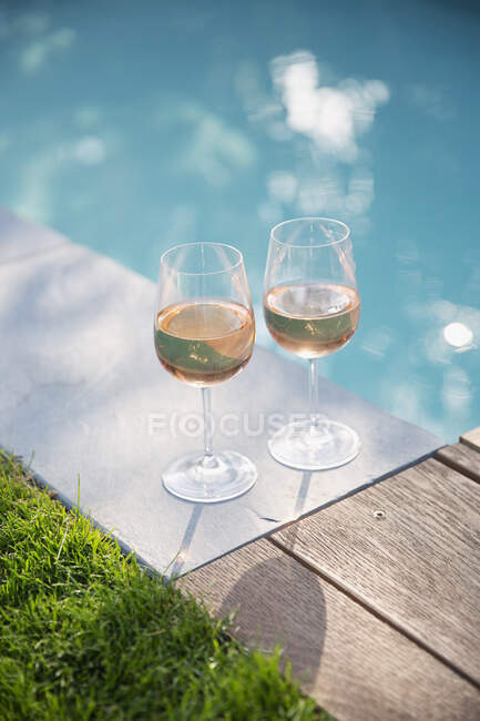 Розовое вино в солнечном, спокойном летнем бассейне — стоковое фото