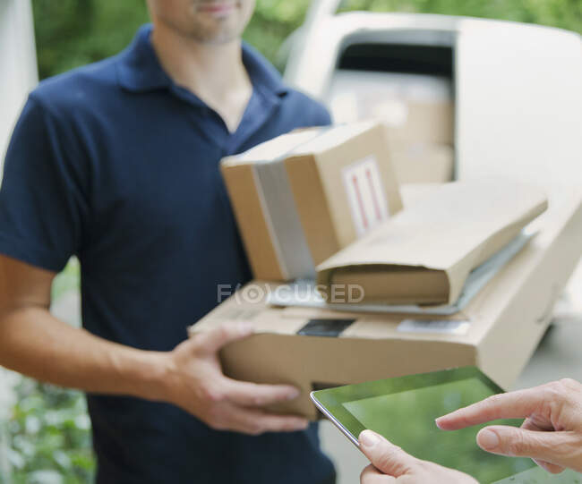 Woman signing digital tablet for deliveryman — Stock Photo