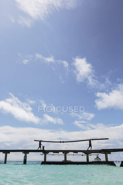 Чоловіки на сонячному причалі над океаном під блакитним небом, Мальдіви. — стокове фото