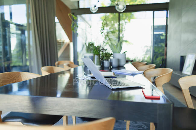 Trabajar desde casa, portátil y teléfono inteligente en la mesa de comedor - foto de stock
