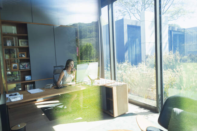 Femme d'affaires travaillant à l'ordinateur dans un bureau à domicile ensoleillé — Photo de stock