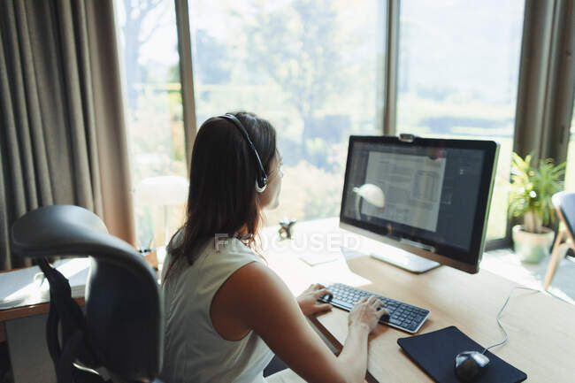 Businesswoman with headset working at computer in home office — Stock Photo