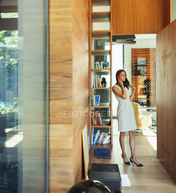 Sorridente donna d'affari che parla su smart phone in corridoio a casa — Foto stock