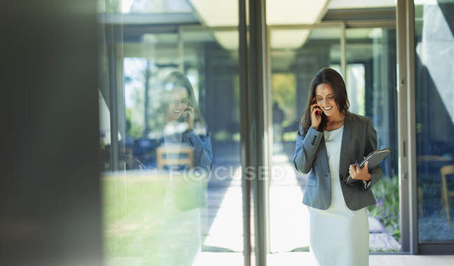 Деловая женщина разговаривает по смартфону в солнечном коридоре — стоковое фото