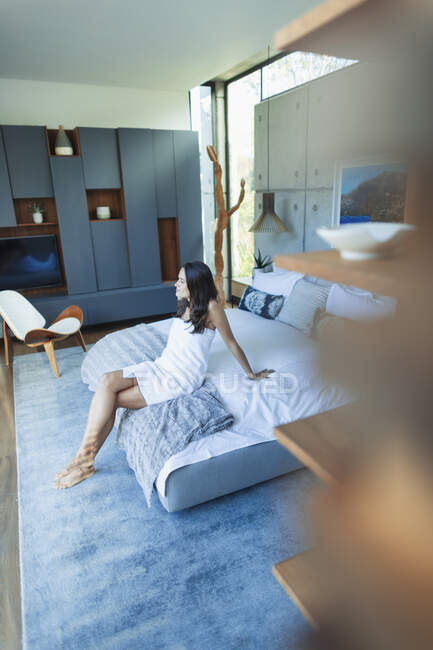 Жінка, загорнута в рушник, розслабляється на ліжку в сучасній спальні — стокове фото