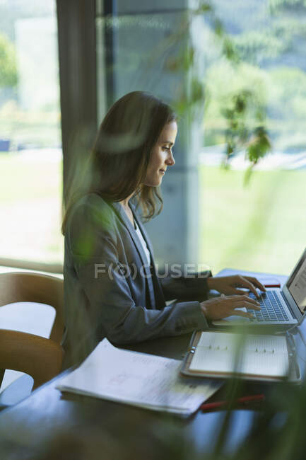 Empresaria enfocada trabajando en laptop - foto de stock