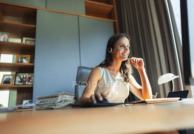 Sorrindo designer de interiores do sexo feminino com fone de ouvido trabalhando em casa escritório — Fotografia de Stock