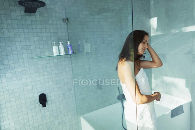 Femme enveloppée dans une serviette dans une douche moderne — Photo de stock