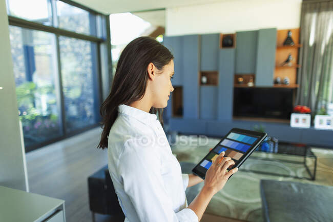 Diseñadora de interiores femenina mirando muestras de color digital en la tableta digital - foto de stock