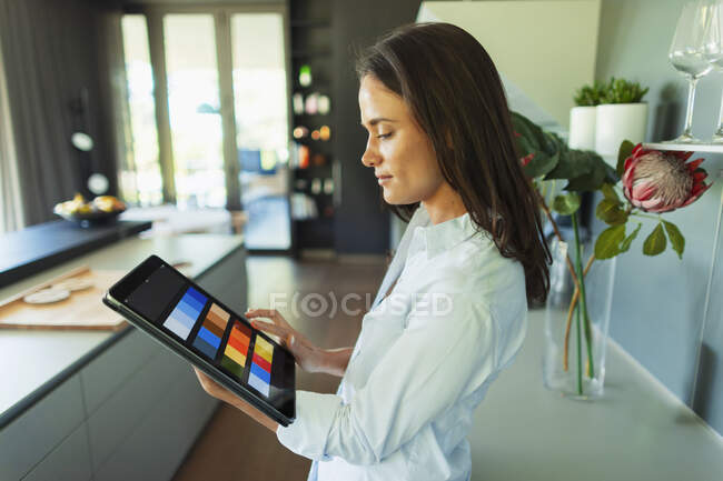 Дизайнер интерьеров смотрит на цифровые цветные образцы на цифровой планшет — стоковое фото
