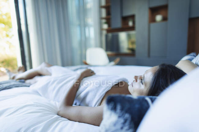 Femme sereine enveloppée dans une serviette, relaxante au lit — Photo de stock