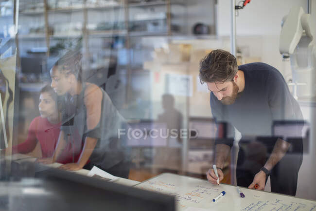 Creative businessman writing on whiteboard, planning and brainstorming in office — Stock Photo