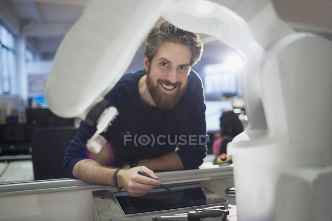 Портрет впевнений інженер з цифровим планшетом, що керує роботизованою рукою — стокове фото